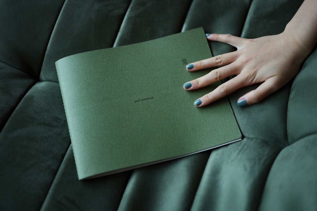 a-womans-hand-resting-on-a-green-book-whhbbpytibm
